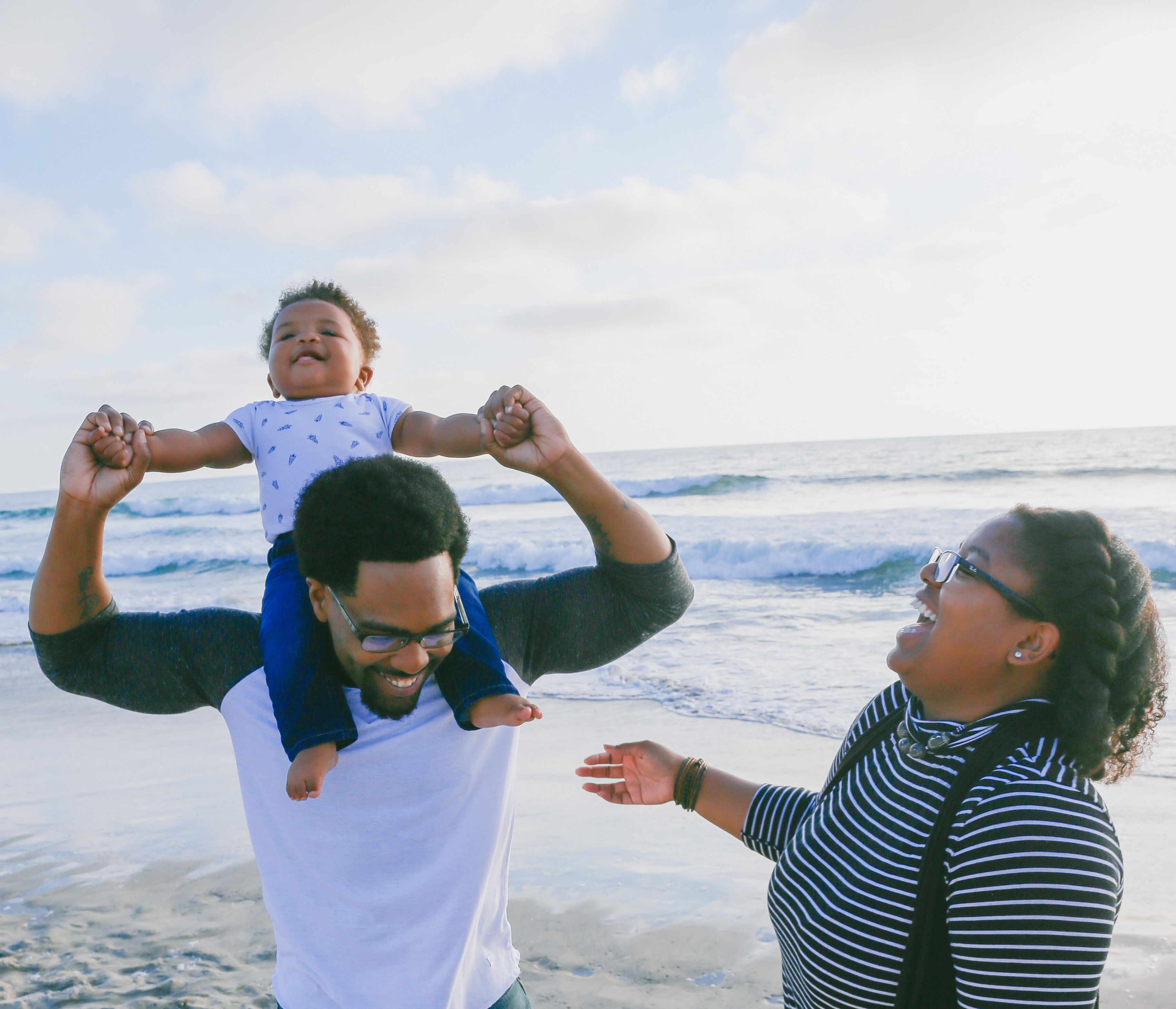 A man with a kid on his shoulders, and a woman, all three laughing. Credit: Lawrence Crayton on Unsplash